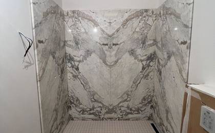 Процесс облицовки стен ванной комнаты крупноформатными плитами мрамора Калакатта (Calacatta).